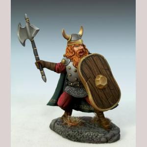 A bearded male dwarf warrior standing defensively. He is wearing a plate armour breastplate with a chainmail vest beneath. Trousers, boots and a three quarter length cloak. A two horned helmet protects his head, and a large shield is held close to his body. His other hand holds a large single bladed axe, ready to strike.