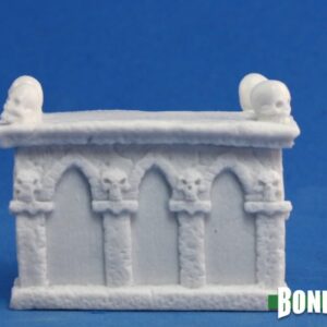 A rectangular altar with a flat top and a human skull on each top corner. Unpainted plastic RPG tabletop gaming miniature.