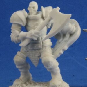 An undead skeleton wearing heavy plate armour. In one hand it holds a short handled, large headed single bladed axe, at chest height. In the other a skull shaped shield.. Unpainted plastic RPG tabletop gaming miniature.